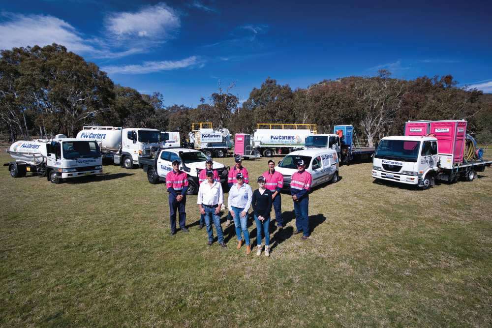 The Poo Carters team standing with their fleet of trucks and portable toilets, showcasing their service for clients in the Yass, and Queanbeyan-